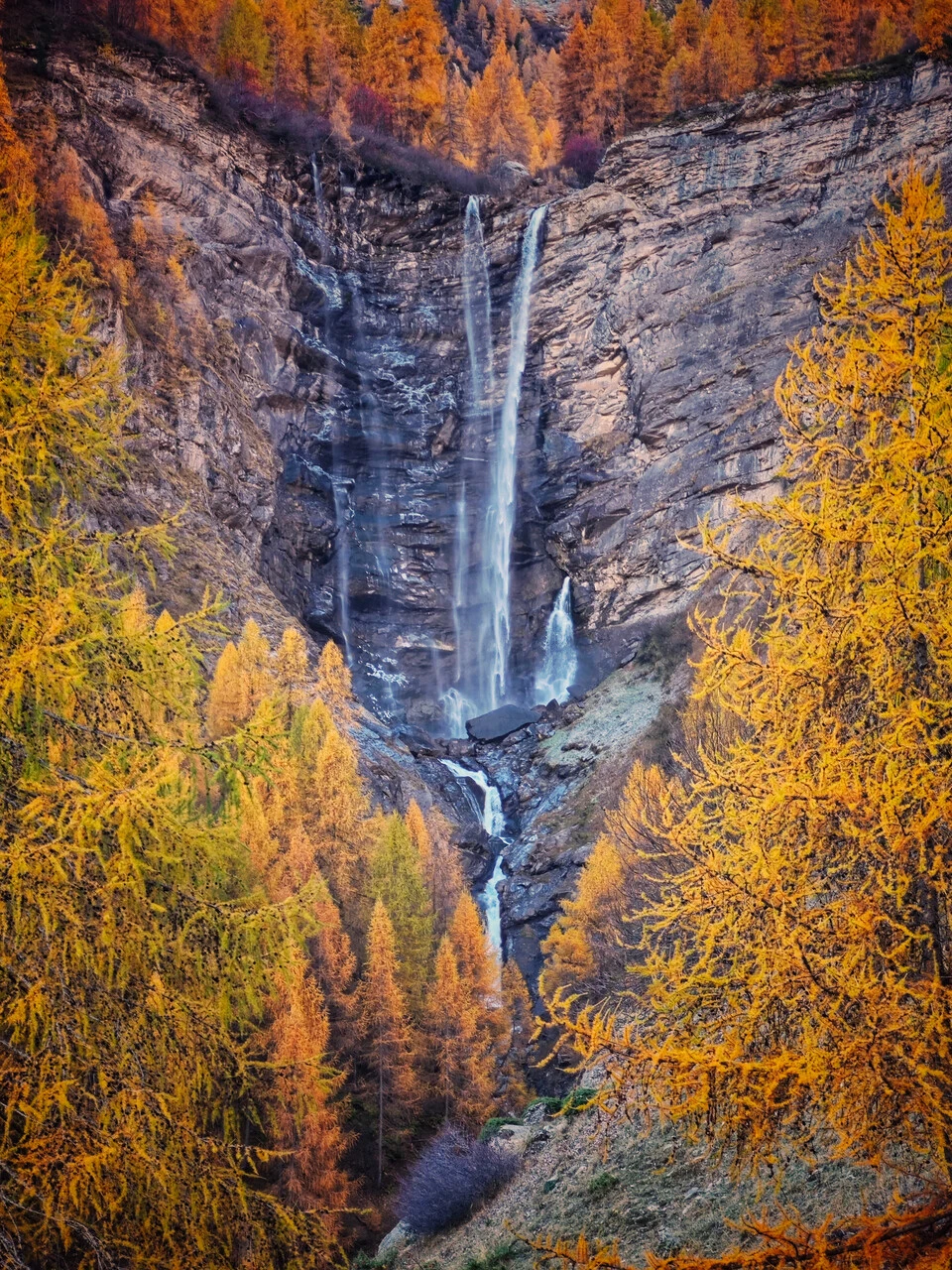 The cascade de la Pisse at Champoléon, among the fall larches